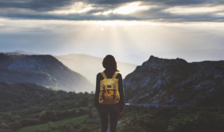 woman wearing a backpack looking out at a mountain view for article on what to know as an esl teacher going abroad